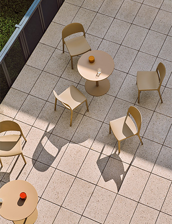Garden set with sand-coloured chairs and tables on a tiled terrace, seen from above.