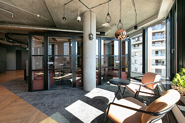A lounge area in the office overlooking the city, equipped with soft armchairs, tables and booths for focused work.